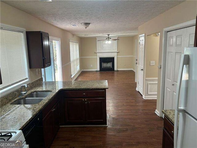 kitchen with white appliances, dark wood-type flooring, a textured ceiling, and stone counters