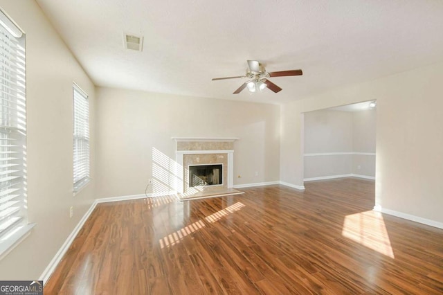 unfurnished living room with ceiling fan, dark wood-type flooring, and a fireplace