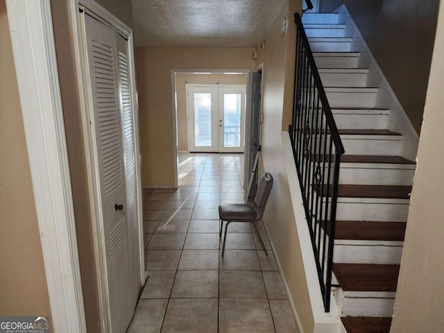 interior space featuring french doors, a textured ceiling, and light tile patterned floors