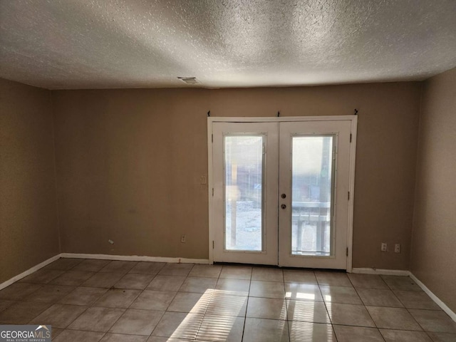 doorway with light tile patterned floors, a textured ceiling, and french doors