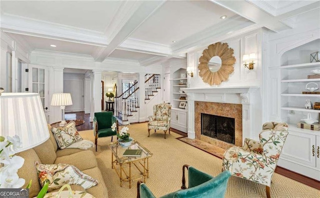 living room featuring built in shelves, coffered ceiling, beam ceiling, a fireplace, and decorative columns