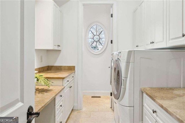 washroom with washer and dryer and cabinets