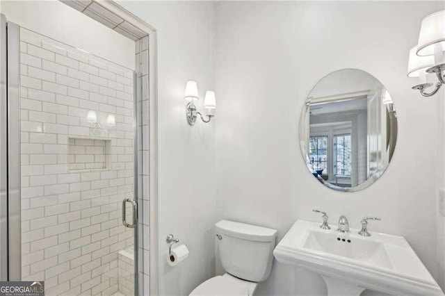 bathroom featuring sink, an enclosed shower, and toilet