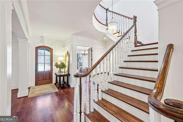 foyer entrance with crown molding, dark hardwood / wood-style flooring, and a notable chandelier