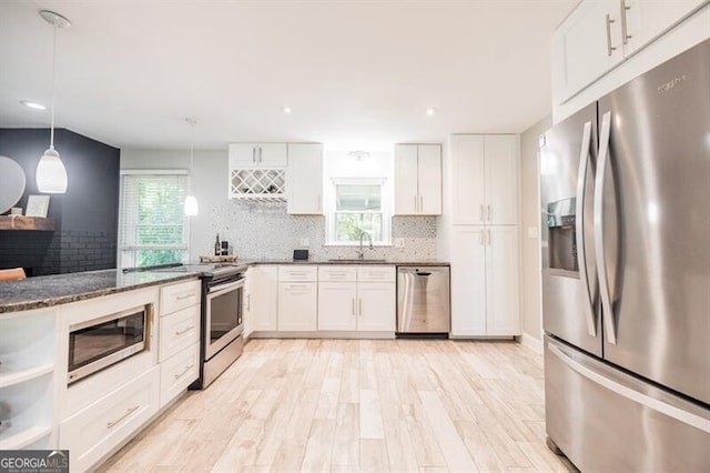 kitchen featuring white cabinetry, stainless steel appliances, decorative light fixtures, and sink