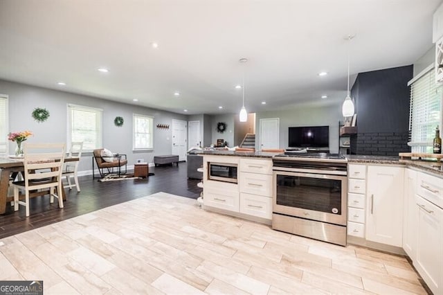 kitchen featuring appliances with stainless steel finishes, pendant lighting, tasteful backsplash, white cabinetry, and light hardwood / wood-style floors