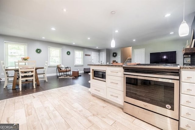 kitchen with stainless steel appliances, white cabinetry, pendant lighting, and light hardwood / wood-style flooring