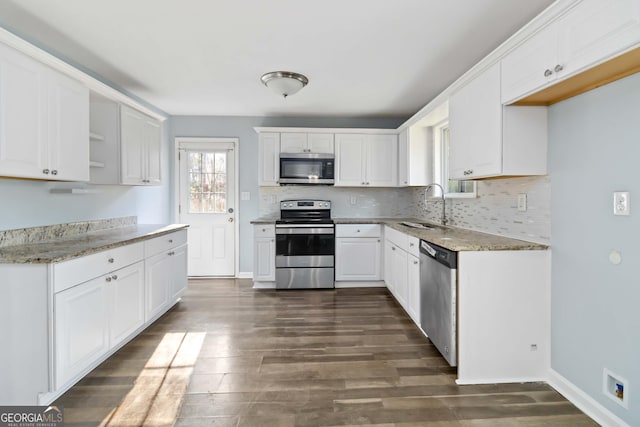 kitchen with white cabinetry, sink, light stone countertops, and appliances with stainless steel finishes