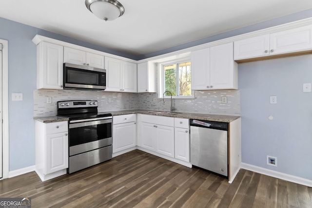 kitchen with stainless steel appliances, white cabinetry, light stone countertops, and sink