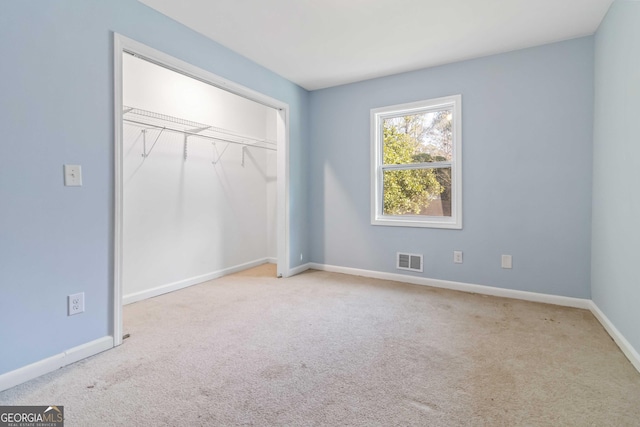 unfurnished bedroom with a closet and light carpet