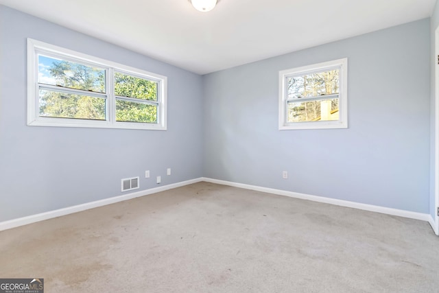 spare room featuring light colored carpet and a healthy amount of sunlight