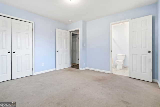 unfurnished bedroom with light colored carpet, ensuite bath, and a closet