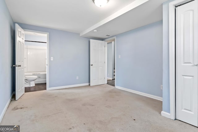 unfurnished bedroom featuring light colored carpet and ensuite bathroom