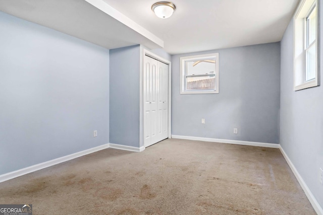 unfurnished bedroom with multiple windows, carpet flooring, and a closet