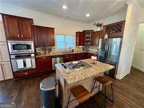 kitchen featuring a kitchen island, dark hardwood / wood-style flooring, a kitchen breakfast bar, light stone counters, and stainless steel appliances