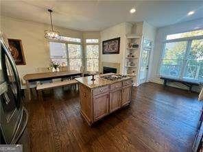 kitchen with dark hardwood / wood-style floors, decorative light fixtures, a center island, and light stone counters