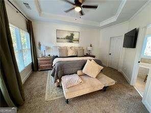 bedroom with crown molding, a raised ceiling, ceiling fan, and dark colored carpet