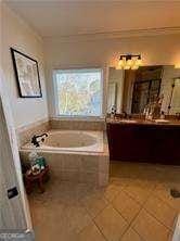 bathroom with vanity, a relaxing tiled tub, and tile patterned floors