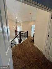 hallway featuring an inviting chandelier and carpet