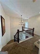 hall featuring crown molding, carpet floors, and a chandelier