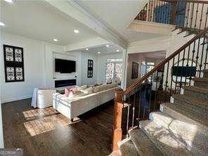 living room with crown molding, dark wood-type flooring, and beam ceiling