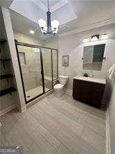 bathroom with a chandelier, ornamental molding, vanity, walk in shower, and toilet