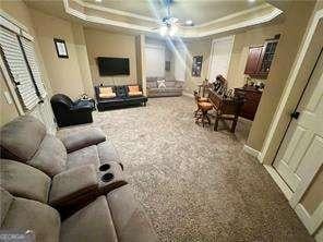 carpeted living room featuring ceiling fan and a raised ceiling