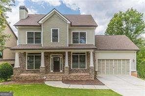 view of front of property featuring a porch, a garage, and a front lawn