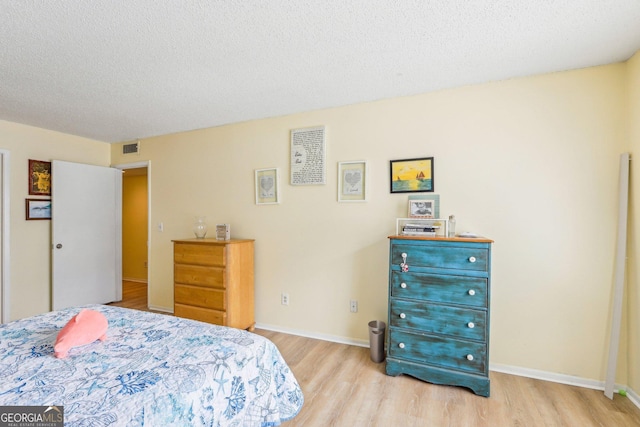 bedroom with light hardwood / wood-style floors and a textured ceiling