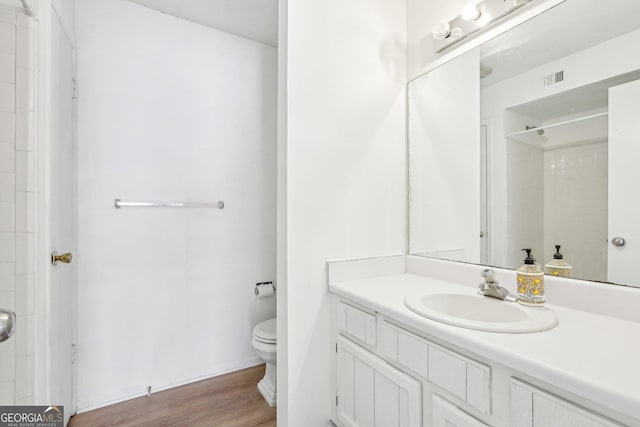 bathroom featuring wood-type flooring, a shower, vanity, and toilet