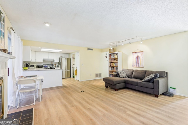 living room with a textured ceiling and light wood-type flooring