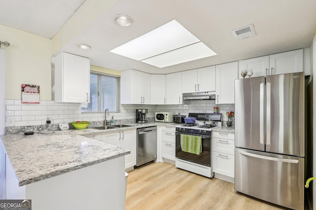 kitchen featuring sink, white cabinetry, appliances with stainless steel finishes, kitchen peninsula, and light stone countertops