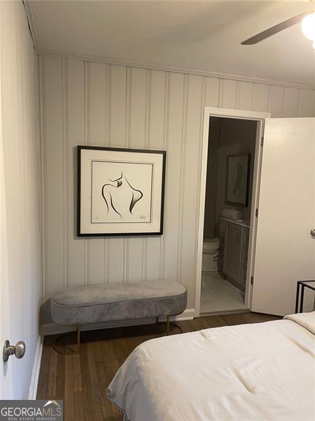 bedroom featuring ceiling fan, connected bathroom, and dark hardwood / wood-style floors