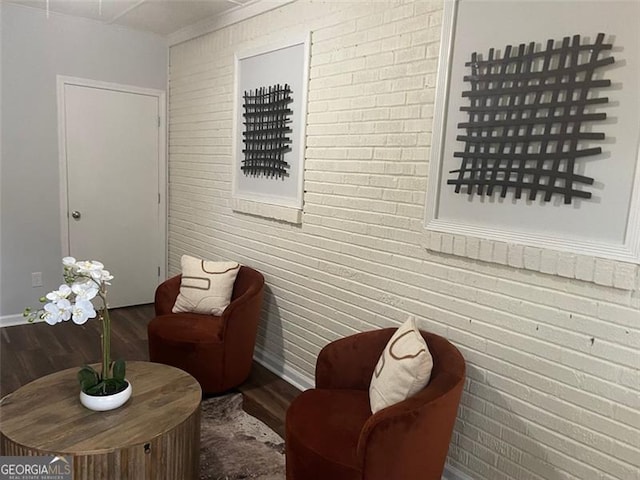 sitting room featuring hardwood / wood-style floors and brick wall