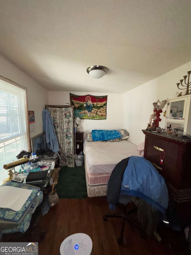 bedroom with dark hardwood / wood-style floors and a textured ceiling