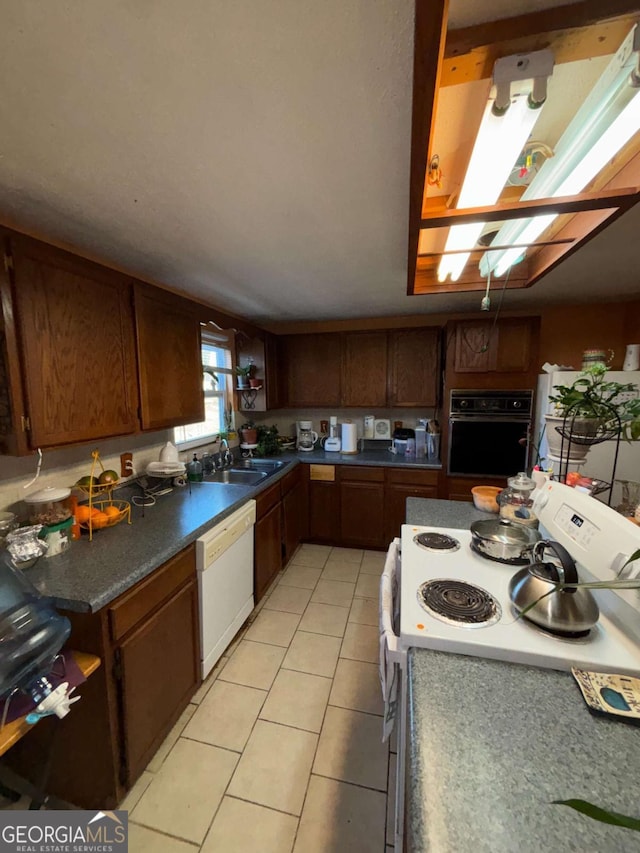 kitchen with sink, light tile patterned floors, and white appliances