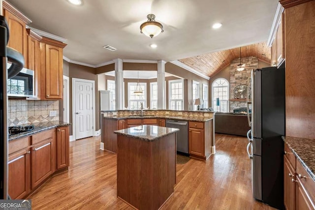 kitchen featuring stainless steel appliances, a center island, and dark stone countertops