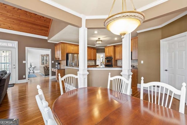 dining room featuring decorative columns, crown molding, and dark hardwood / wood-style floors