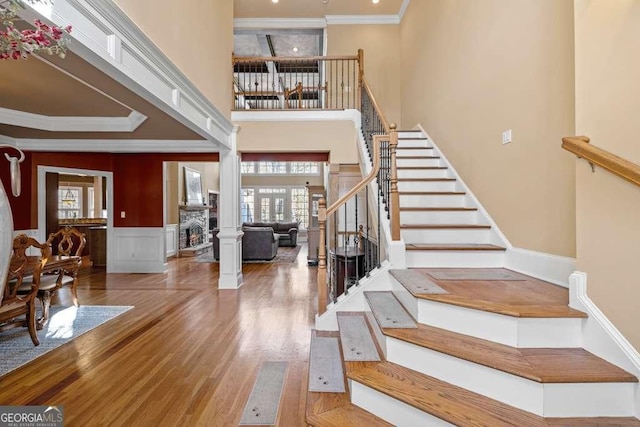 entrance foyer featuring hardwood / wood-style flooring, ornamental molding, a high ceiling, and ornate columns