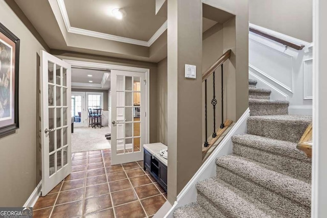 interior space featuring french doors, a tray ceiling, tile patterned flooring, and crown molding