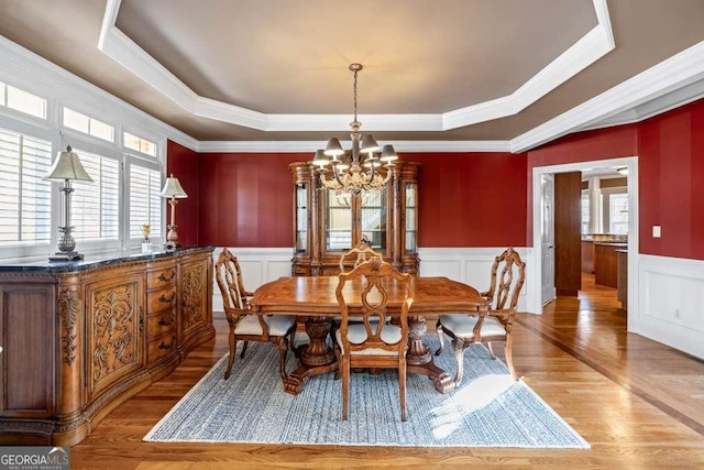 dining area featuring a chandelier, crown molding, a raised ceiling, and light hardwood / wood-style flooring