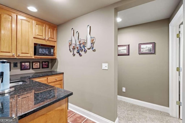 kitchen featuring light carpet, black microwave, and dark stone countertops