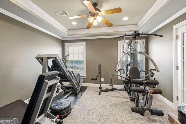 exercise area with ceiling fan, ornamental molding, and a tray ceiling