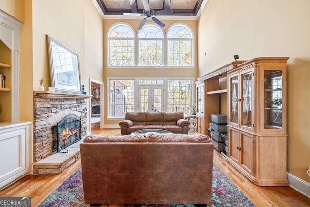 living room featuring french doors, a stone fireplace, and light wood-type flooring