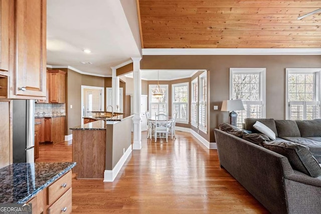 living room with crown molding, a wealth of natural light, light hardwood / wood-style floors, and decorative columns