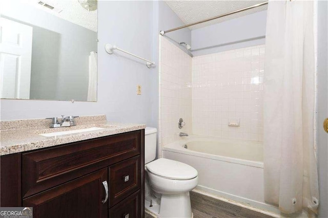 full bathroom with shower / bathtub combination with curtain, vanity, wood-type flooring, a textured ceiling, and toilet