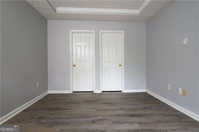 unfurnished bedroom featuring crown molding, a tray ceiling, dark hardwood / wood-style floors, and a textured ceiling