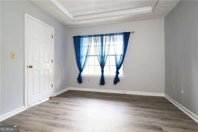 spare room featuring crown molding, a raised ceiling, hardwood / wood-style floors, and a textured ceiling