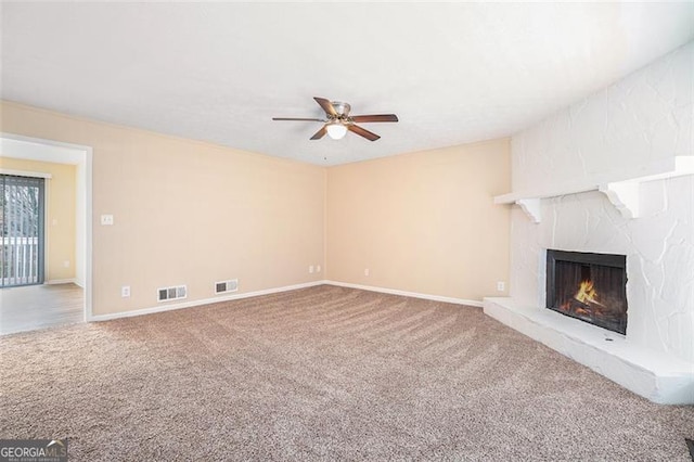 unfurnished living room with ceiling fan, a large fireplace, and carpet