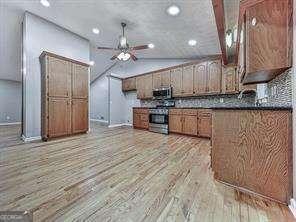 kitchen featuring ceiling fan, stainless steel appliances, light hardwood / wood-style floors, and lofted ceiling